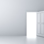 Opened door with bright light on empty white wall background